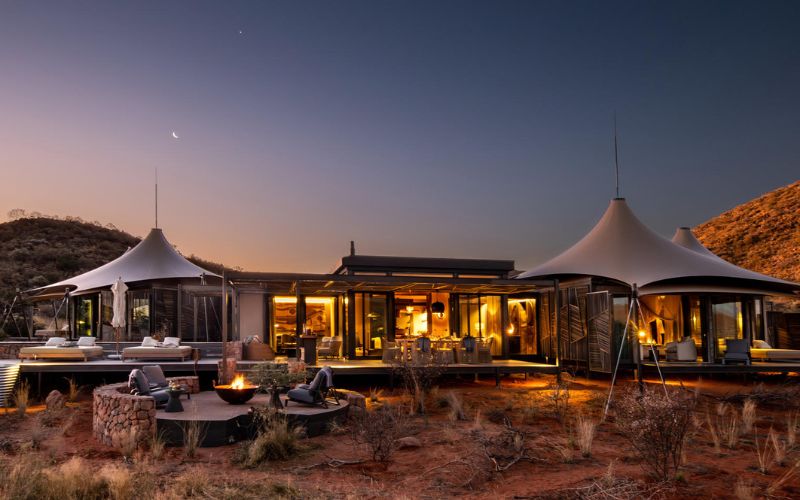 Luxury safari lodge in the Kalahari glowing at dusk, offering outdoor dining and desert views during a tailor-made African safari with Marula Hill Travel.